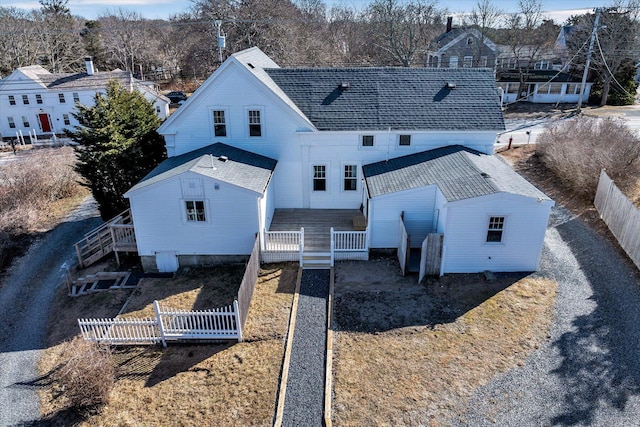 rear view of property featuring a shingled roof and fence