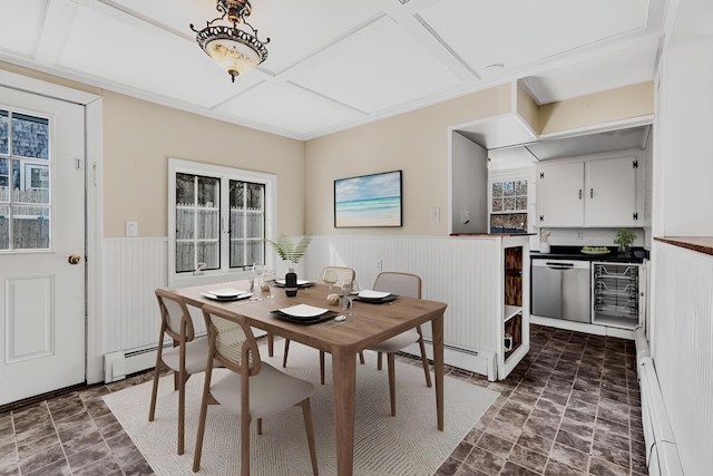 dining area with a baseboard heating unit, a baseboard radiator, a wealth of natural light, and a wainscoted wall