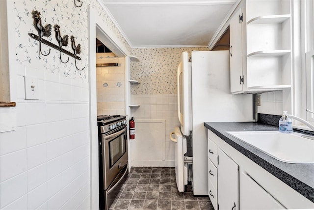 kitchen featuring a sink, gas stove, open shelves, dark countertops, and wallpapered walls