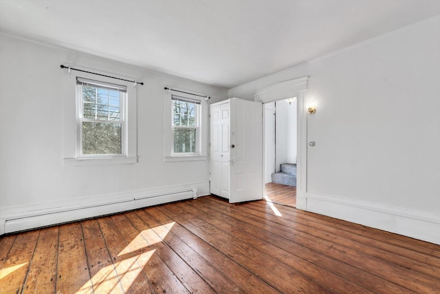 unfurnished room with a baseboard heating unit, stairway, and hardwood / wood-style flooring