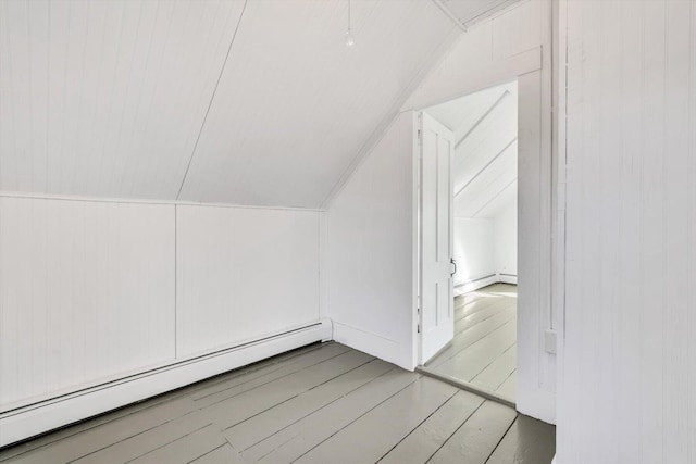 additional living space with lofted ceiling, a baseboard radiator, and wood finished floors