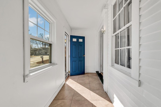 interior space with a healthy amount of sunlight, crown molding, and light tile patterned floors