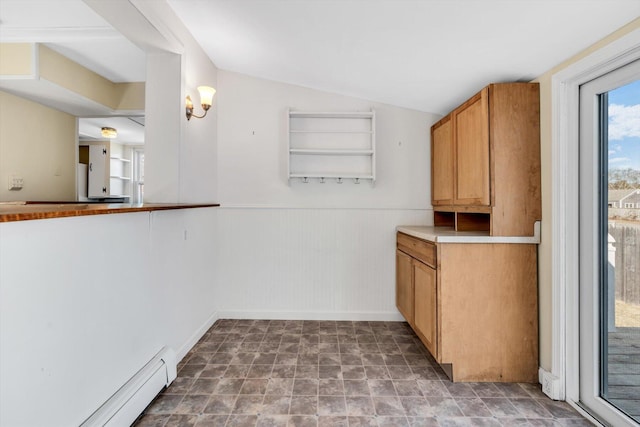 interior space featuring lofted ceiling, light countertops, baseboard heating, and wainscoting