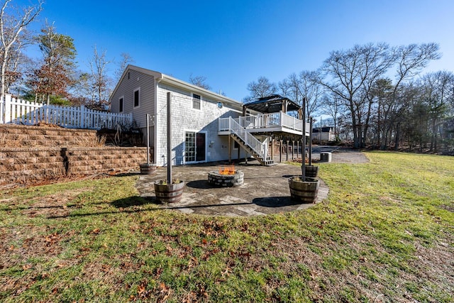 rear view of house with a fire pit, a gazebo, a lawn, and a deck