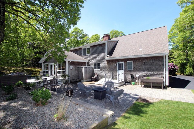 473 Thousand Oaks Dr, Brewster, MA 02631 - rear view of house with a chimney, a patio, a shingled roof, an outbuilding, and a fire pit