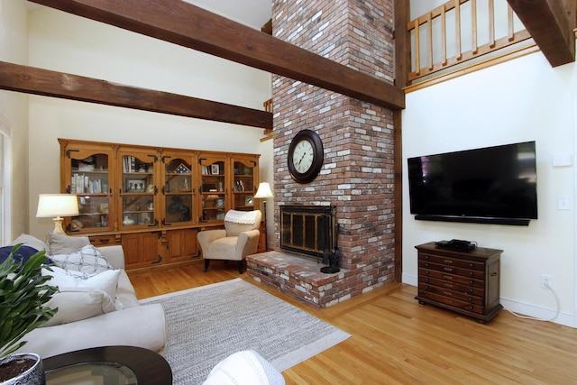 473 Thousand Oaks Dr, Brewster, MA 02631 - living area featuring wood finished floors, a fireplace, a towering ceiling, baseboards, and beam ceiling