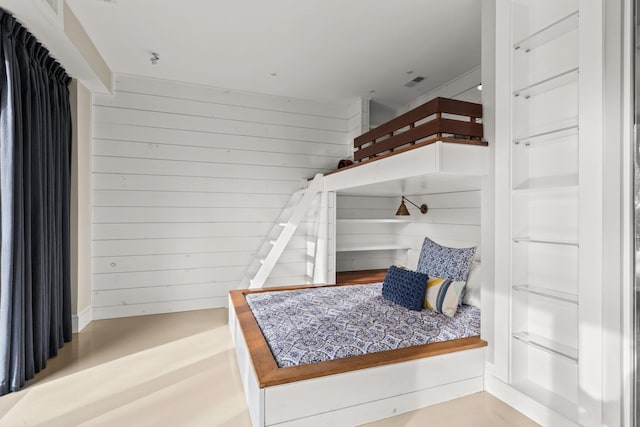 bedroom with wood walls and concrete floors