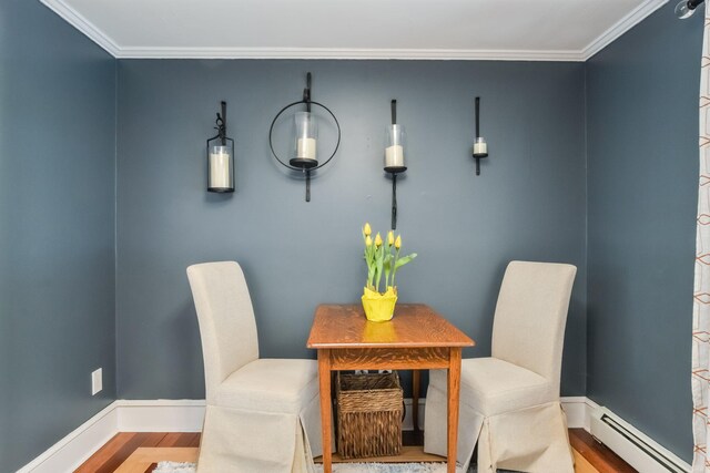 dining area with baseboards, baseboard heating, wood finished floors, and crown molding