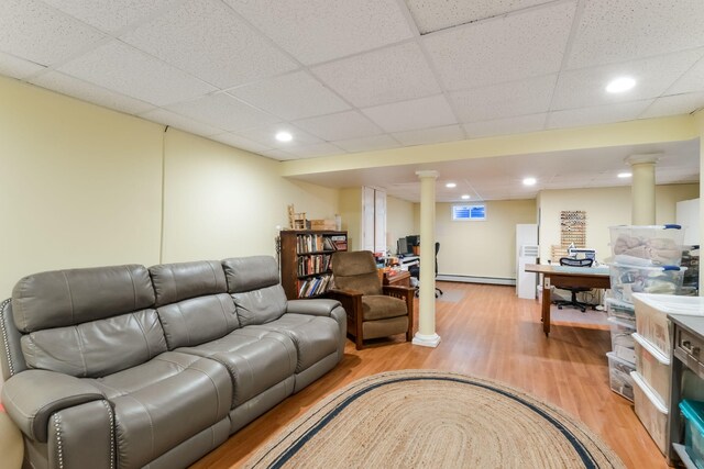 living area with baseboard heating, recessed lighting, light wood-type flooring, and a drop ceiling