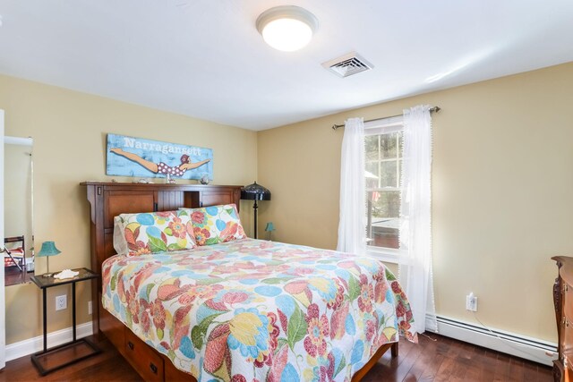 bedroom featuring a baseboard heating unit, wood finished floors, visible vents, and baseboards