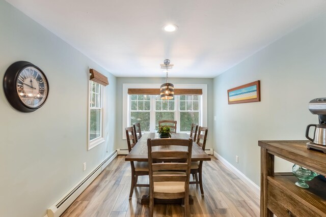 dining space featuring a baseboard radiator, baseboards, a notable chandelier, and light wood finished floors