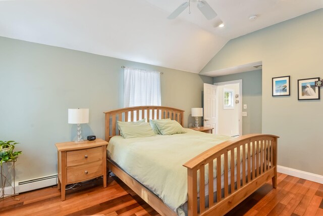 bedroom featuring a baseboard heating unit, wood finished floors, baseboards, lofted ceiling, and ceiling fan