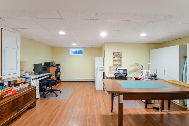 office space featuring a drop ceiling, recessed lighting, light wood-style floors, and baseboard heating