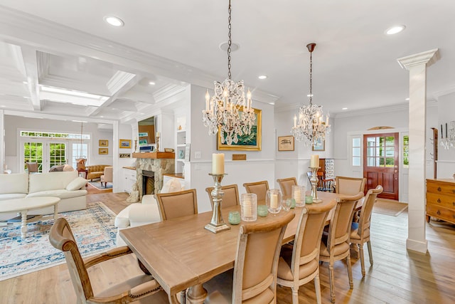 dining area featuring coffered ceiling, a healthy amount of sunlight, a fireplace, and light wood-type flooring