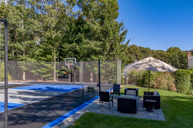 view of sport court featuring tennis court and a lawn