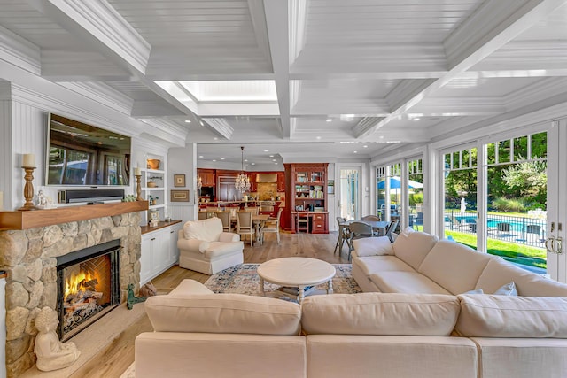 living room with a fireplace, beamed ceiling, ornamental molding, coffered ceiling, and light hardwood / wood-style floors