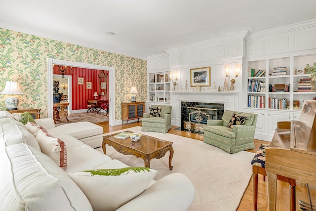 living room featuring ornamental molding, built in shelves, a fireplace, and light hardwood / wood-style flooring