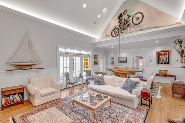 living room with french doors, ornamental molding, light hardwood / wood-style floors, and high vaulted ceiling