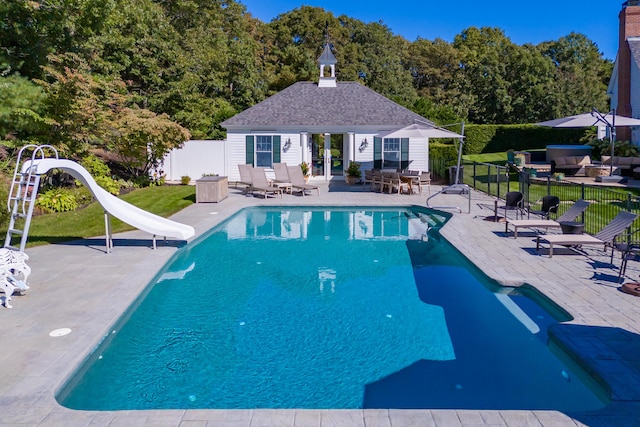 view of swimming pool featuring an outbuilding, a patio, and a water slide