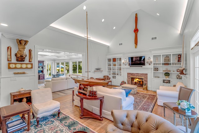 living room with ornamental molding, a fireplace, high vaulted ceiling, and light wood-type flooring