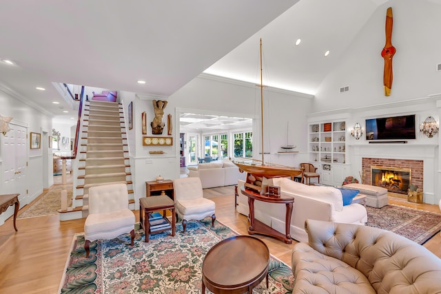 living room featuring ornamental molding, high vaulted ceiling, a brick fireplace, and light hardwood / wood-style flooring