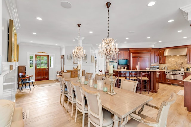 dining space featuring crown molding, an inviting chandelier, and light hardwood / wood-style floors