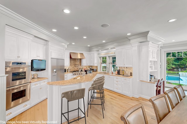 44 Seapuit Rd, Osterville, MA 02655 - kitchen with appliances with stainless steel finishes, a sink, ornamental molding, white cabinetry, and wall chimney exhaust hood