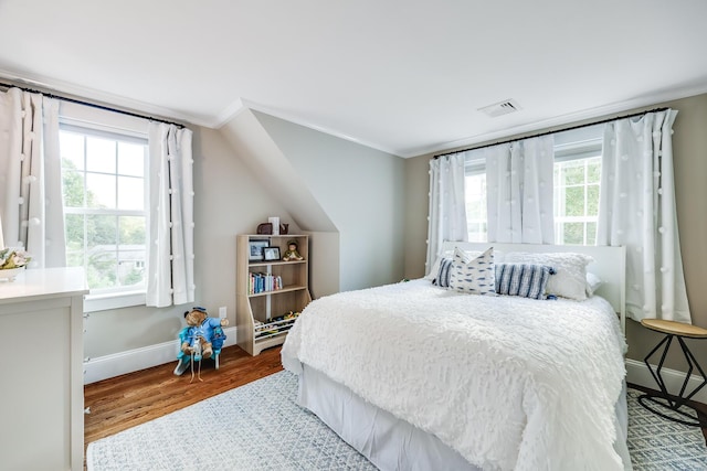 bedroom featuring hardwood / wood-style floors, multiple windows, and ornamental molding