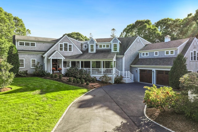 view of front of house featuring a garage, covered porch, and a front lawn