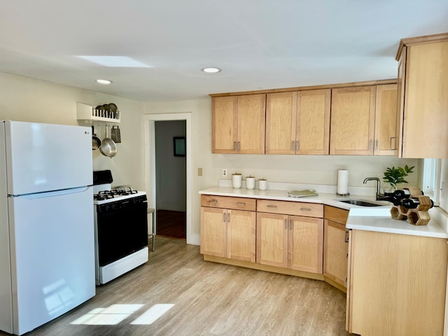 kitchen with light hardwood / wood-style floors, gas range oven, white fridge, sink, and light brown cabinets