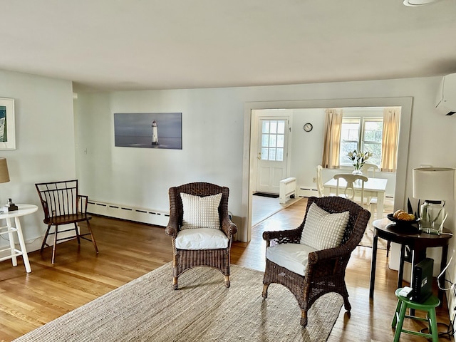 living area featuring light hardwood / wood-style floors, a baseboard radiator, and a wall mounted air conditioner