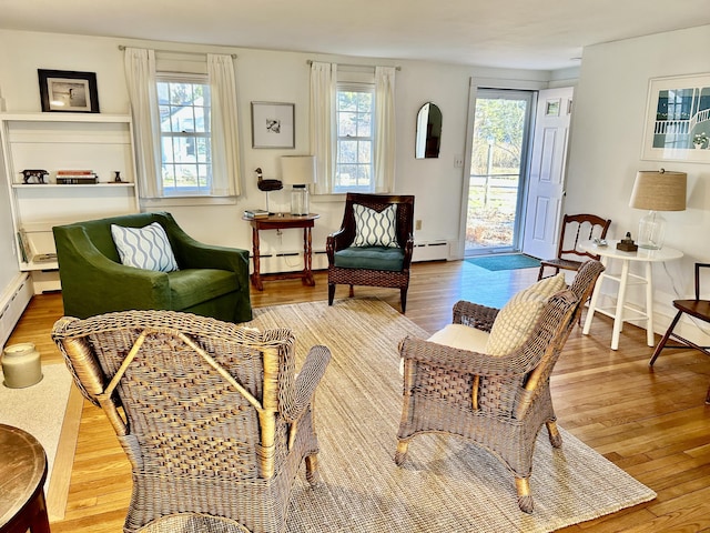 sitting room featuring wood-type flooring, a baseboard radiator, and a wealth of natural light