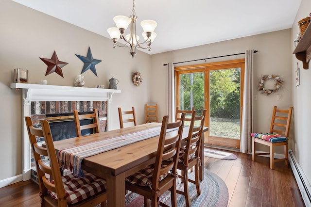 dining area featuring a notable chandelier, a baseboard heating unit, wood finished floors, baseboards, and a brick fireplace