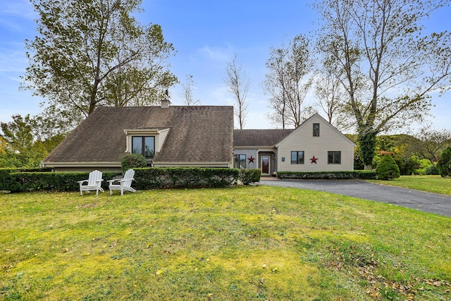 view of front of property with a chimney, a front lawn, and aphalt driveway