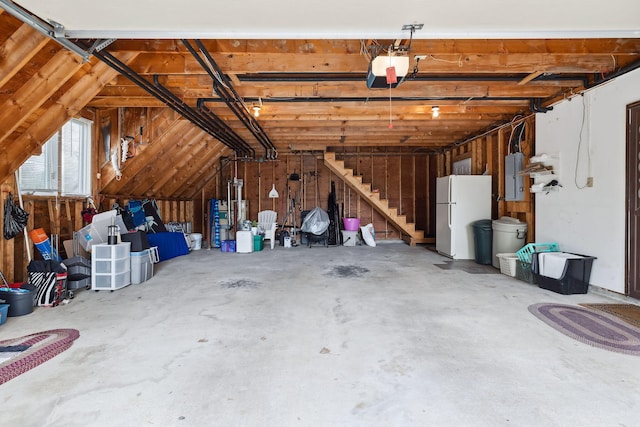 garage featuring electric panel, freestanding refrigerator, and a garage door opener