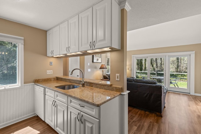 kitchen with dark wood-style flooring, white dishwasher, white cabinetry, and a sink