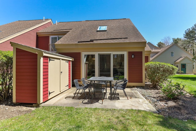 back of property with roof with shingles, a storage shed, an outbuilding, a lawn, and a patio