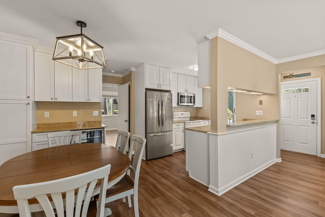 kitchen featuring a notable chandelier, stainless steel appliances, white cabinetry, dark wood-type flooring, and ornamental molding