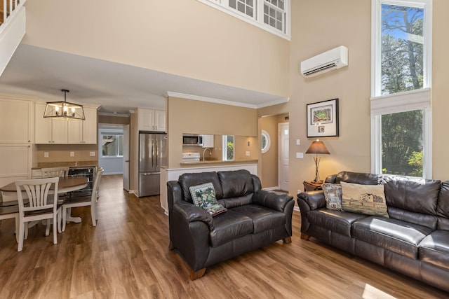 living room with an inviting chandelier, a high ceiling, dark wood finished floors, and a wall unit AC