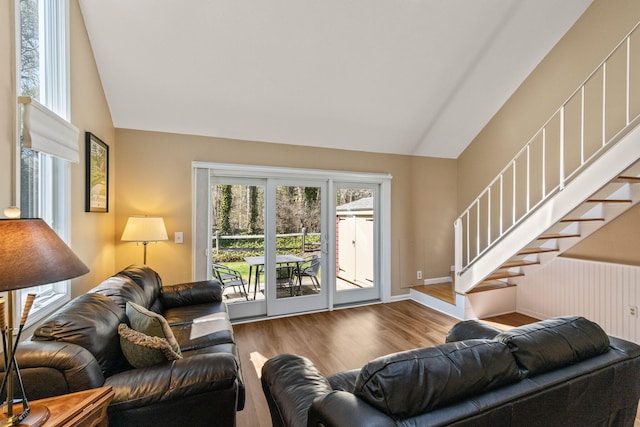 living area featuring baseboards, plenty of natural light, stairs, and wood finished floors