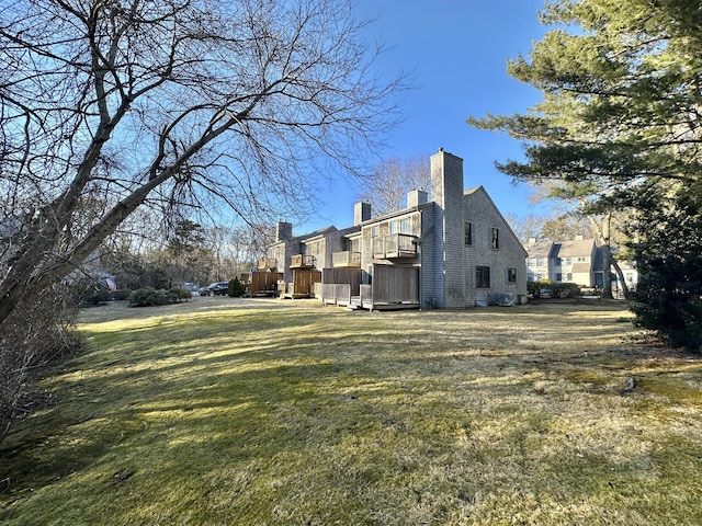 view of property exterior featuring a chimney, a deck, and a lawn