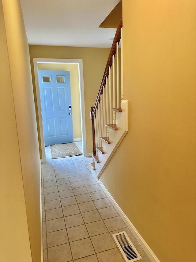 foyer featuring stairs, light tile patterned flooring, visible vents, and baseboards