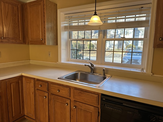 kitchen with brown cabinetry, dishwasher, light countertops, pendant lighting, and a sink