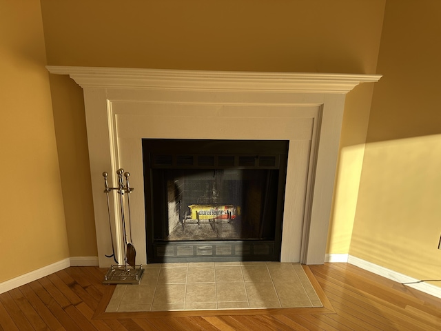 interior details with a fireplace with flush hearth, baseboards, and wood finished floors