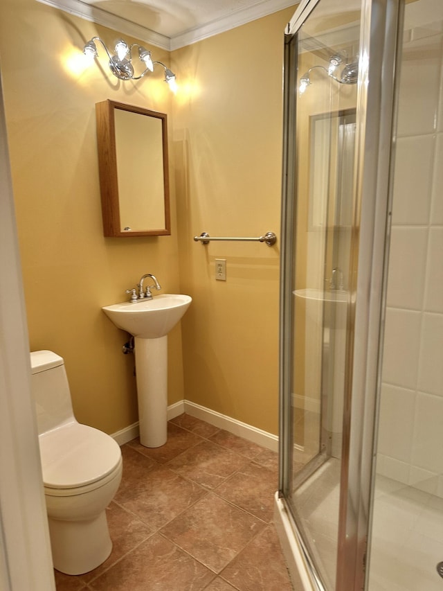 bathroom with toilet, a sink, baseboards, ornamental molding, and a stall shower