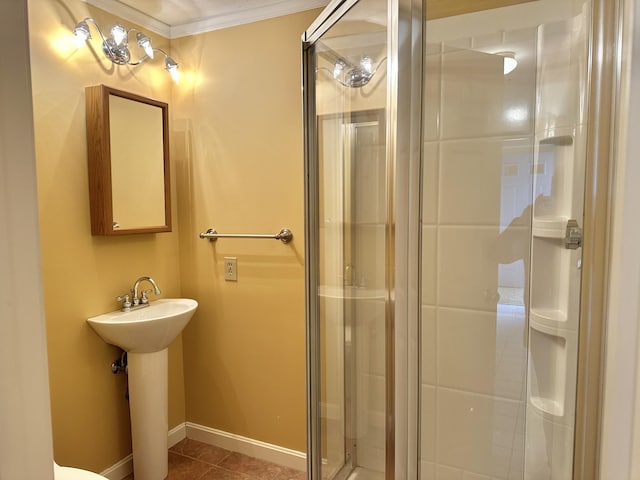 bathroom featuring ornamental molding, a stall shower, a sink, baseboards, and tile patterned floors