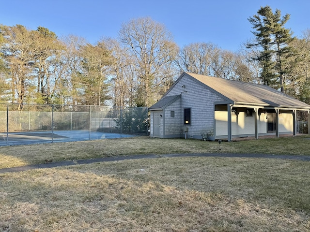 exterior space with a tennis court, fence, and a yard