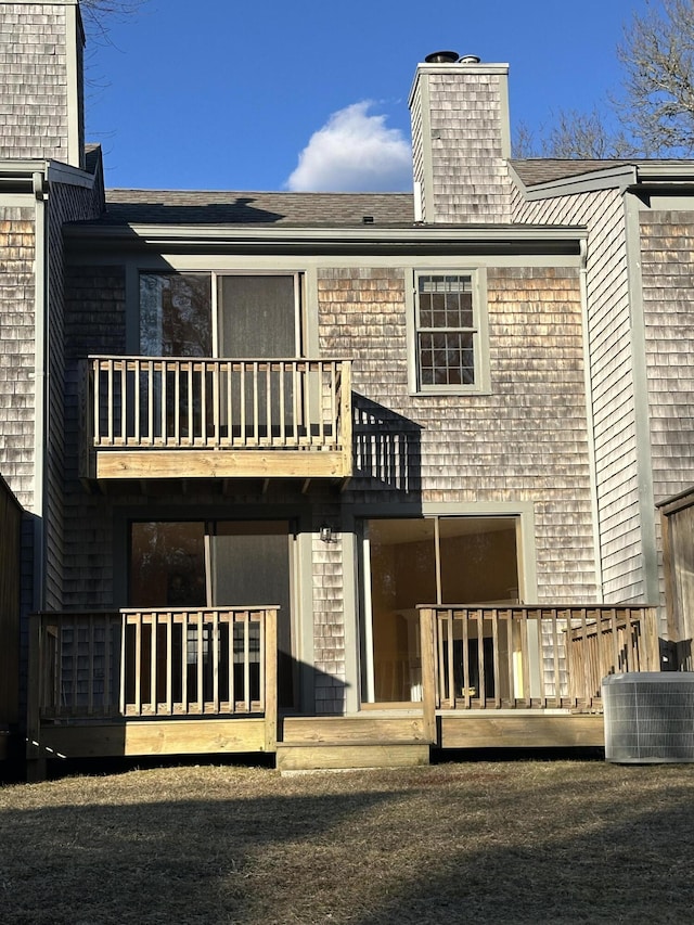 back of house featuring a balcony, a chimney, central AC unit, and a wooden deck