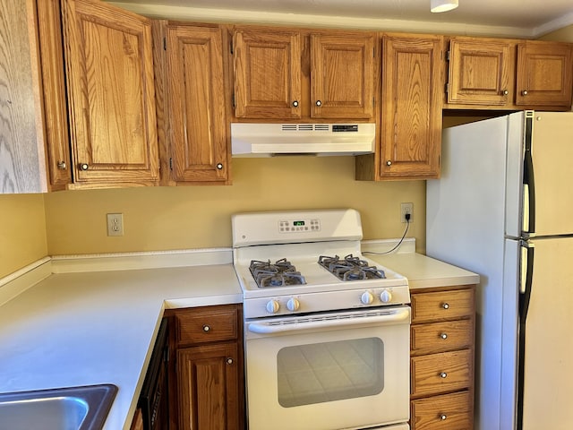 kitchen featuring brown cabinets, white appliances, light countertops, and under cabinet range hood