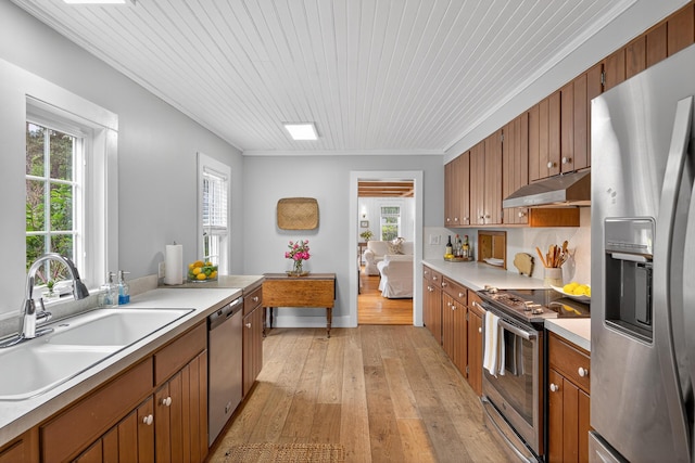77 Pleasant Rd, West Harwich, MA 02671 - kitchen featuring stainless steel appliances, under cabinet range hood, light countertops, brown cabinetry, and light wood-style floors